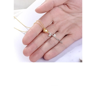 Detail of rose pendant with gold blossom and silver stem held against white background