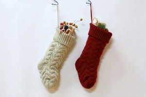 Close-up of beige and red knit Christmas stockings with classic cable pattern on a wall
