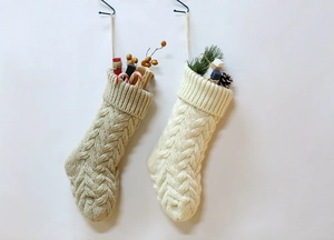 Detail of cable knit Christmas stockings in beige and cream white yarn hanging on hooks