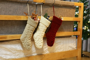 Close-up of cable knit Christmas stockings in cream, oatmeal, and burgundy hanging on wood