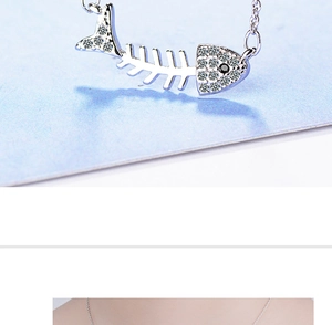 Macro shot of a silver fishbone pendant with zircon stones and a black gem on a necklace