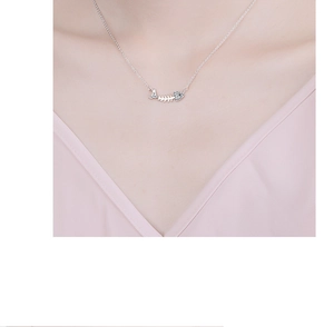 Close-up of a silver fishbone pendant necklace with sparkling rhinestones on the collarbone