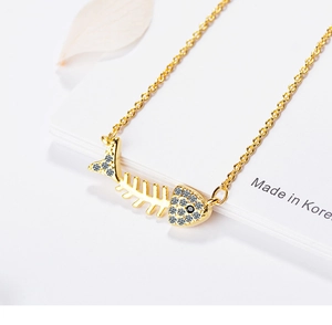 Macro shot of a gold fishbone pendant necklace with sparkling white crystals and black gem