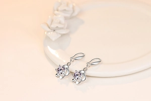 Macro shot of silver plum blossom earrings with clear cubic zirconia on a ceramic plate