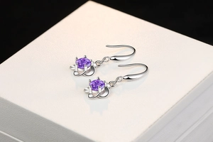 Macro shot of silver drop earrings with purple zircon gemstone in a floral setting
