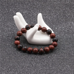 Macro shot of 10mm red mahogany obsidian beaded bracelet on white ceramic display stand