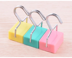 Close-up of colorful magnetic hooks in yellow, cyan, and pink on light wood background