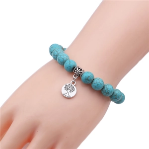 Detail of 10mm turquoise beaded bracelet featuring a silver tree of life charm and cross