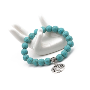 Macro detail of turquoise beaded bracelet featuring a silver tree of life charm and metal beads