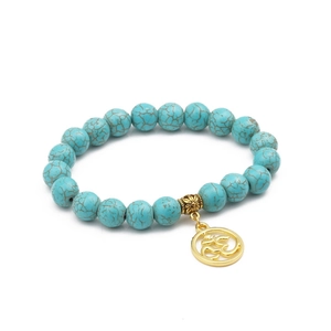 Detail of 10mm turquoise beaded bracelet with golden Om charm on white background