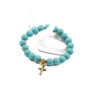 Detailed shot of 10mm turquoise bead bracelet with a gold cross pendant on a hand model