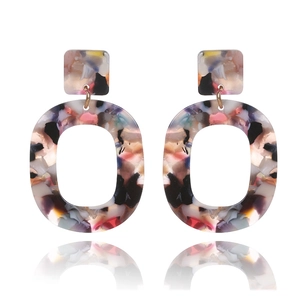 Detail of large oval colorful resin earrings with gold metal studs on white background