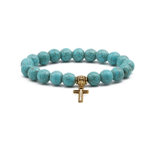 Close-up of 10mm turquoise beaded bracelet with gold hollow cross pendant on white back
