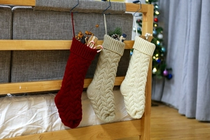 Close-up of cable knit Christmas stockings in burgundy, oatmeal, and cream hanging on wood