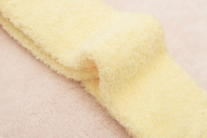 Detail showing the soft yellow coral fleece texture of these warm cartoon monster socks