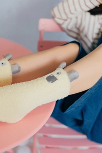 Close-up of yellow fuzzy socks with cute cartoon animal faces on a soft surface
