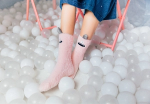 Close-up of pink coral fleece socks featuring monster embroidery and grey ear details