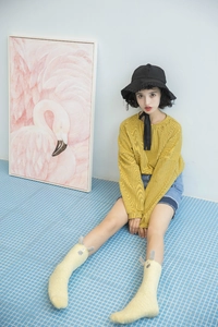 Close-up of yellow plush monster-style socks worn by a model on blue tiles