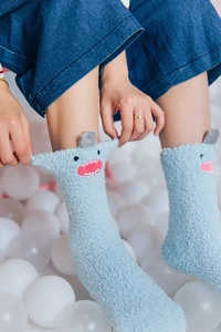 Detail of blue plush shark socks with grey fin accents and cute coral fleece texture