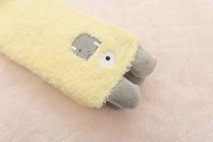 Close-up of yellow monster coral fleece sock with gray embroidered face and soft plush texture