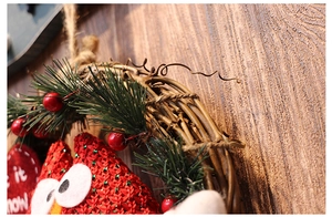 Detail of knitted owl with red berries and pine needles on a natural vine wreath base