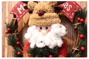 Close-up of Christmas wreath with plush Santa and Reindeer on a warm wooden background