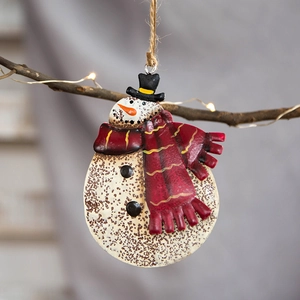 Vintage metal snowman Christmas ornament with red scarf and black hat on festive tree