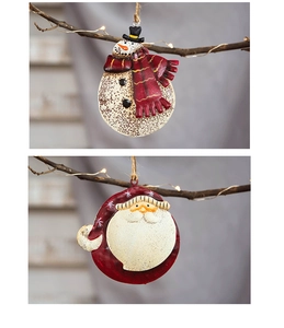 Detail of vintage iron Santa Claus and snowman ornaments hanging on a rustic branch