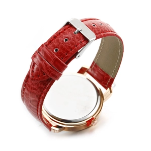 Detail of red crocodile texture strap and polished rose gold buckle closure on women watch