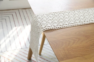 Detail of hand-woven beige cotton linen table runner with hollow floral pattern