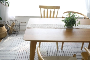 Detail of handmade crochet lace table runner on solid wood dining table in rustic style