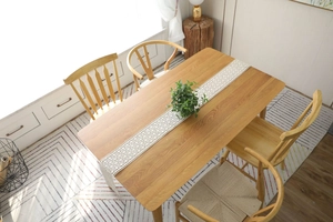 Detail of a beige crochet lace table runner on a rustic wooden dining table setup