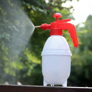White plastic pressure sprayer for gardening shown spraying water on a wooden surface