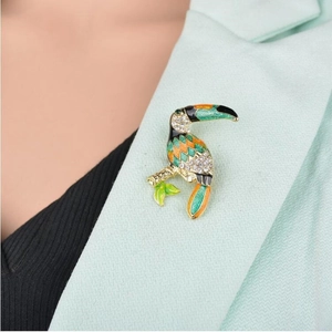 Detailed macro view of a colorful toucan brooch pinned to a light green suit lapel