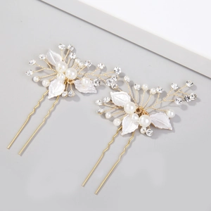 Detailed shot of golden bridal hair pins with white frosted leaves and pearls