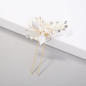 Detailed view of bridal hair pin with white leaves, pearls and crystals on gold U-shape pin