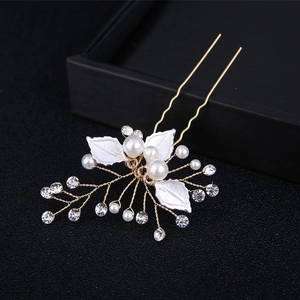 Macro detail of handmade bridal hair pin with white leaves, pearls and gold wire accents