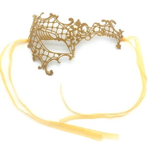 Macro detail of golden lace phoenix mask with silk ribbons for masquerade party props
