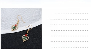 Detail view of heart-shaped Christmas earrings with green tree and red rhinestones