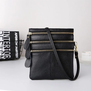 Detail view of a black multi-zipper leather crossbody bag with adjustable shoulder strap