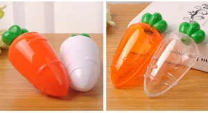 Carrot-shaped plastic candy boxes in orange and clear colors shown on a desk