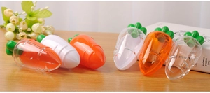 Carrot-shaped plastic candy boxes in orange and clear colors on a wooden table surface