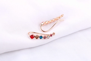 Detail of rose gold ear crawlers with gradient multi-colored zircon crystals on fabric