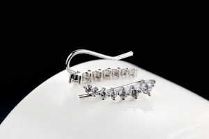 Macro shot of silver ear crawler earrings with gradient cubic zirconia on ceramic base