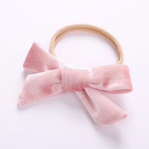Detail of pink velvet bow on a soft nude nylon baby headband for infants