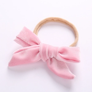 Detail of soft pink velvet bow on elastic beige nylon headband for babies