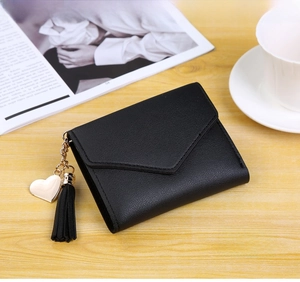 Detail of black envelope wallet featuring lychee texture leather and heart tassel charm