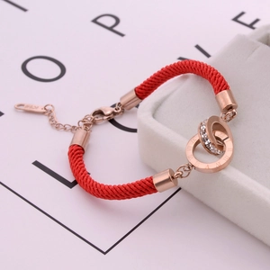 Detail of rose gold double rings on red string bracelet with roman numerals and crystals
