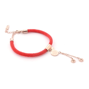 Detailed close-up of rose gold charms and red woven cord bracelet with K14 tag
