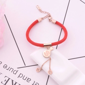 Macro shot of rose gold lucky charms on red woven string with dollar sign and coin details